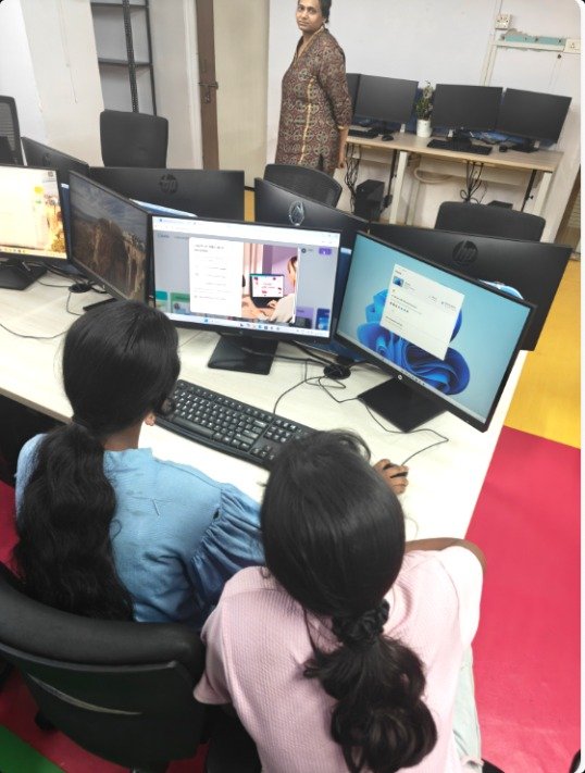 Two students learning on a computer with an instructor nearby